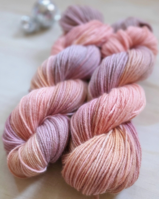 Two skeins of pink and purple yarn on a light background
